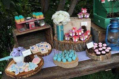 Sweets on a dessert table sat upon slabs of rustic logs.