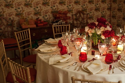 The table at a holiday dinner thrown for close friends displayed a clear vase filled with cranberries, peonies, roses, and pepper berries.