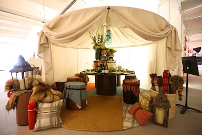 Harley Ellis Deveraux's table for HBF/Gunlocke had a camping-inspired look. The installation held candlelit lanterns, old suitcases, plaid pillows and blankets, pinecones, and baskets filled with worn cooking utensils.