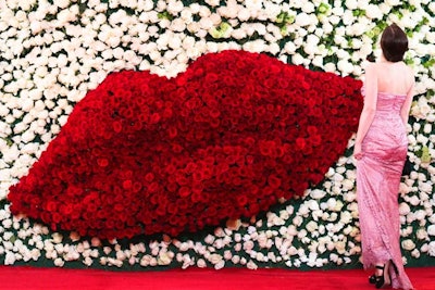 As guests entered New York's Metropolitan Museum through the Great Hall for the Costume Institute gala, they met a 24-foot-tall cynlinder covered in 40,000 roses from Colombia and Ecuador with a lip pattern inspired by Schiaparelli and Prada designs. A team of 150 staffers worked to prepare the floral decor.