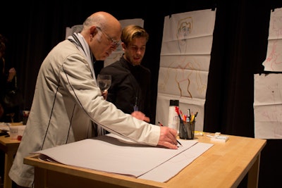 Tables set up on one side of the room held long sheets of paper and drawing instruments for the gala's version of the surrealist art technique known as exquisite corpse. The activity invited guests to draw individual panels as part of a larger piece, resulting in a collection of bizarre, colorful, and collaborative works that decorated a section of the event.