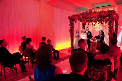 The final ceremony look had a fall theme, with bold red lighting, a chuppah covered in gerbera daisies, and an aisle runner lined with fabric autumn leaves.
