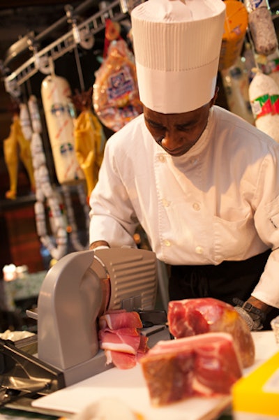 Below the rack, a chef used an industrial slicer to shave meats.
