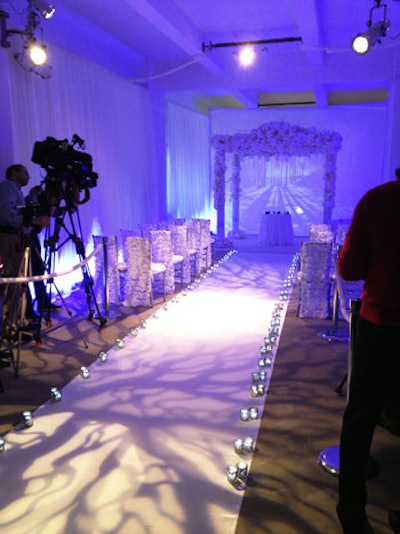 Awash in icy blue light, the first ceremony had a winter theme. Levy Lighting projected a snowy scene behind the altar and bare tree branches onto the white aisle runner.