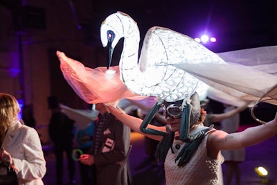 A trio of performers wearing illuminated swan headdresses floated through the room in a silent procession.