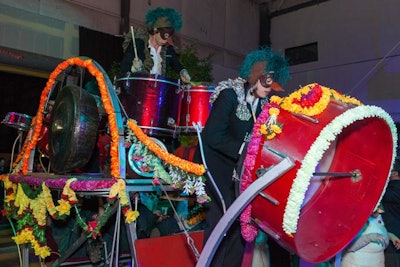 Referred to as the 'drum cart,' a three-tiered, pedal-powered contraption held several percussion instruments. Drummers dressed in bird masks and feathery headdresses commandeered the instruments as they rode the cart through the warehouse space.