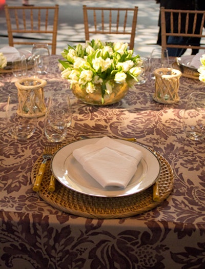 Aerin Lauder designed a table for Kravet that showcased her yet-to-be-released fabric collection for Lee Jofa, covering the table and surrounding walls in a purple damask-patterned linen. The table settings included rattan chargers and bamboo flatware.