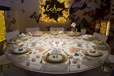 Echo Design’s table celebrated nature by encasing artfully arranged insects, butterflies, and shells inside a clear tabletop. Several of the company’s patterned scarves were backlit on the surrounding walls.