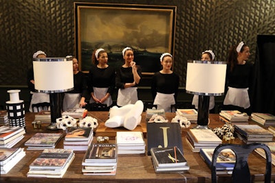 Models clad in French maid uniforms occupied a library/parlor room, where light furnishings and period books were used as props to recreate a posh environment.