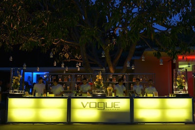 Lanterns hung above an illuminated bar that was topped with flowers and glasses encased in ice.