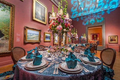 Gallery 4 is home to many classic paintings that feature the color blue. In turn, the three dinner tables had blue velvet damask linens with matching chair cushions. A similar damask gobo on the ceiling drew the eye upward along with the tall candelabra centerpieces of pink, purple, coral, and red roses.
