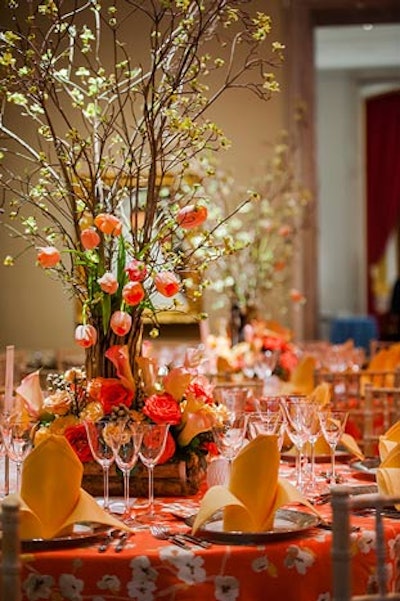 Small Lincoln Log-style wood boxes filled with pink, coral, and orange tulips, roses, and calla lilies topped each of the tables.