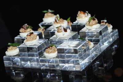 Creative Edge Parties catered the event, serving hors d'oeuvres, such as plum roast chicken atop a scallion 'pillow' (pictured), on Lucite reflective patterned cube trays that playfully placed the food at different heights.