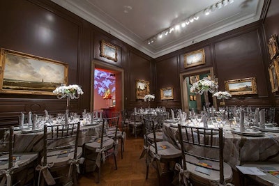 The team softened the natural masculinity and darkness of the wood walls in the Small Mantel Room by using a light color palette of white, light grey, and metallic linens and chairs.