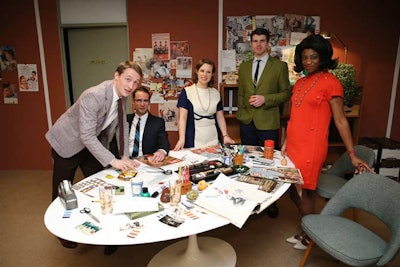 In the Mad Men vignette, guests entered an advertising office circa 1967 complete with a neutral-toned carpeted hallway and walls decorated with framed posters of various campaigns. As they come upon the open-plan space, they were met by a large central table surrounded by magazine cutouts, Pantone swatches, and scribbled notes. The actors in the set assumed a bevy of roles, from throwing paper airplanes while laying on a couch, to walking in and brashly throwing down an assignment.