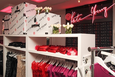 Simple white rectangular shelves and silver rolling racks displayed the Kate Young for Target merchandise. Topping each shelf grouping was a series of branded trunks accented with white roses. Kate Young's name was also, once again, featured in neon pink script.