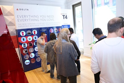 A kiosk near the entrance of the pop-up dispensed travel items frequently purchased at an airport. Complimentary Delta items included a rubber luggage ID tag, compact mirror, and mug, while iPhone cases, Beats headphones, and other accessories were available for purchase. The vending machine represented the expanded retail selection in the new terminal. While in line, guests could play with a 3-D touch-screen model of the terminal that displayed information, images, and video of the new space.