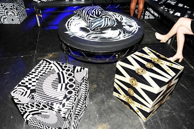 Throughout the general seating area as well as the V.I.P. stage, which was raised eight inches off the ground, the 74 tables and benches were covered with custom hand-stenciled cushions, a decorative throwback to the Versus aesthetic. Guests were also given gold lion's head safety pins and rubber bracelets as a souvenir from the night.