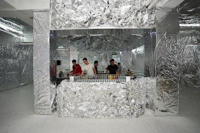 While the main party space was wall-to-wall Mylar, the four bars and the DJ booth were sculpted with thick aluminum foil. To light the bar, 600 miniature magnetic LED lights were hung from above. Around 6,500 square feet of recycled Mylar was utilized to cover the walls and ceilings.
