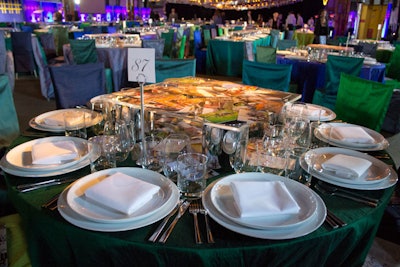 The centerpieces consisted of photos scattered atop raised Lucite platforms, which guests could pick up and look through during the meal. The family-style dinner platters were eventually placed atop the platforms, as well.