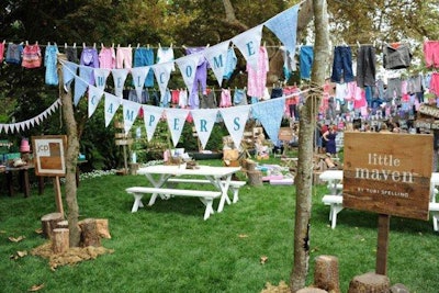 Pieces from the Little Maven clothing collection hung above a kitschy campfire setup on the lawn.