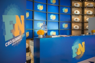 Shiraz designed the registration table in bold blue and yellow. The grid behind it featured the summit logo, and the table held yellow flowers and candy jars with white treats.