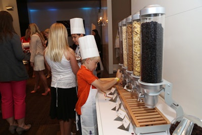 Children filled mini canning jars with their own trail mix at a station that included granola, dried fruits, nuts, and chocolate chips.