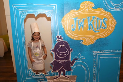 Children wearing toques and JW Kids aprons posed for photos in the art-themed surround.