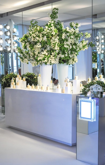 Guests could sample the new moisturizer formula, bottles of which were set up on a table with an arrangement of towering dogwood branches. Lighted signs on the mirrored highboys displayed facts about the Clinique brand and explained the various interactive experiences around the room.