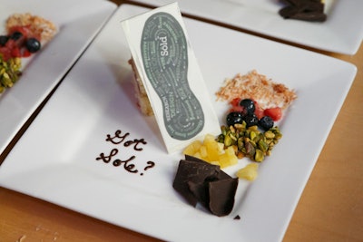 A chocolate shoe sole decorated the dessert of lemon-blueberry pound cake with white-chocolate glaze. The plate was garnished with 'side textures,' which included chocolate shavings, toasted coconut, pistachios, and berry compote.
