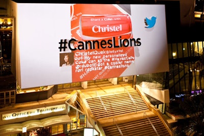 During the day, the billboard above the venue entrance simply displayed the event's hashtag in black letters. As the sun went down each night, a projector mounted on a roof across the street added a 3-D display of tweets and photos that used the official hashtag.