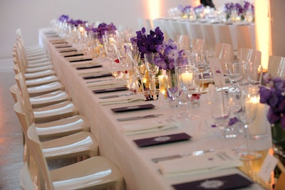Banquet-style dinner tables were given a sleek, modern look with purple orchids and candles arranged atop mirrored runners.