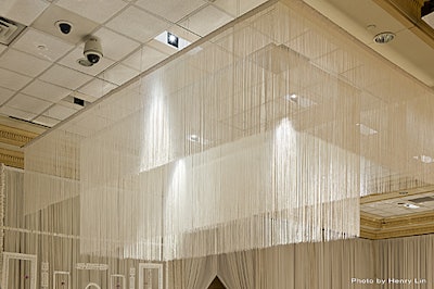 Similar layered style of white string curtains at different heights with spotlight lighting.