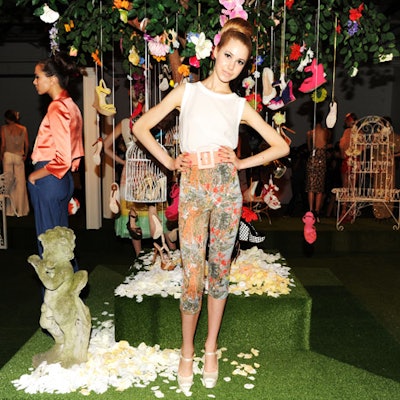 During September Fashion Week in 2011, Alice & Olivia turned a raw studio into a whimsical garden for the showing of its latest collection. Grassy flooring, white lawn furniture, and trees hung with accessories set the scene.