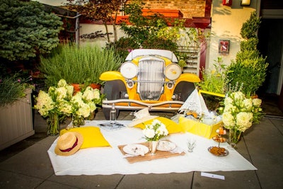Marie Aiello Design Studio’s elegant Great Gatsby picnic spread included fresh flower arrangements, a tiered display of cookies, 1920s-style accessories, and a façade of the yellow 1929 Duesenberg Leonardo DiCaprio drives in Baz Luhrmann’s movie.