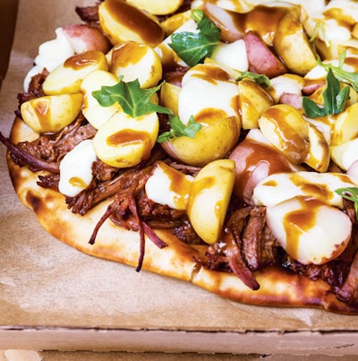 Individual-size poutine pizza in a corrugated cardboard box with potatoes, cheese curds, gravy, and pulled pork, by Entertaining Company in Chicago
