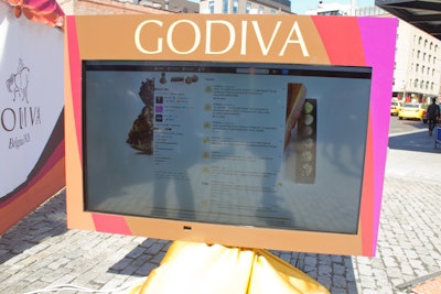 A large screen displayed social media posts about Godiva's truffle flights activation.