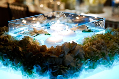 'The icy floating gardenia and candle centerpieces created instant drama, surrounded by ice-blue hydrangea cuffs around the oversize square vases.'