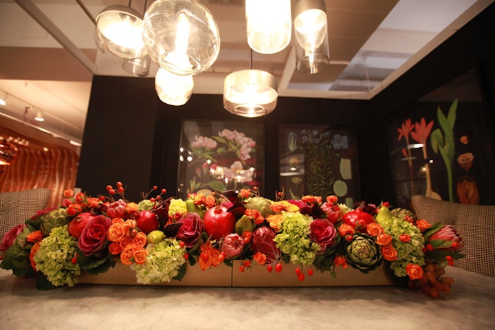 A jewel-hued centerpiece, which contained pomegranates and artichokes as well as flowers, ran down the center of Room & Board's table. On the walls, botanical prints complemented the natural theme.