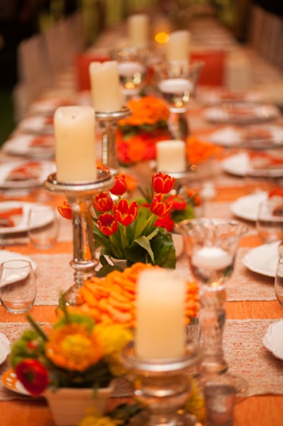 Richard Grille Events mixed pillar candles and votives with tulips and other orange-hued flowers.