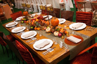 For a fall-hued table, JM Event Design arranged apples, pumpkins, and other gourds into a pleasing cornucopia. Velvet-covered and leather chairs set a warm tone.