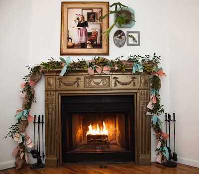 Holiday garlands that included gingham fabric strips decorated the mantel for a warm holiday tableau. Frames of various shapes and sizes completed the hearth.