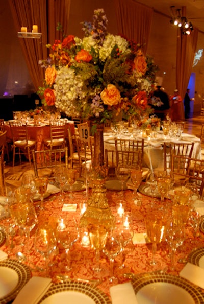 Jack Lucky designed two centerpieces for the dining tables, alternating between larger bouquets of light blue, coral, blue pink, and soft green flowers on two-foot gold pedestals, and shorter boxed arrangements of the same flowers.