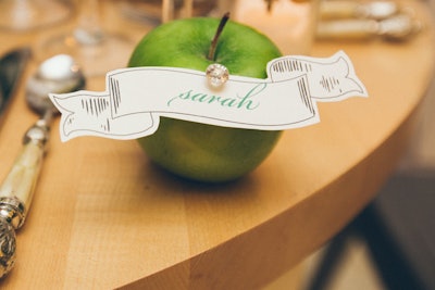 Some place cards are tacked onto green apples with bejeweled pins.