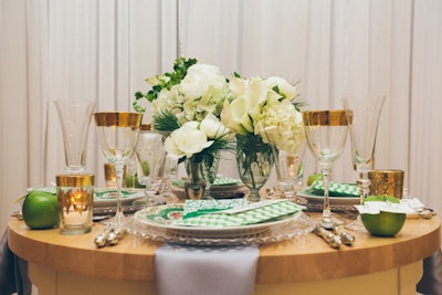 Centerpieces comprise white roses and greenery in apothecary jars.