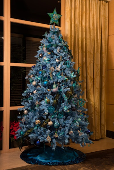 André Wells of Events by André Wells paid homage to the song 'Blue Christmas' with his tree. Multiple shades of blue bulb ornaments, plumes, peacock feathers, and glitter peace signs adorned the branches.