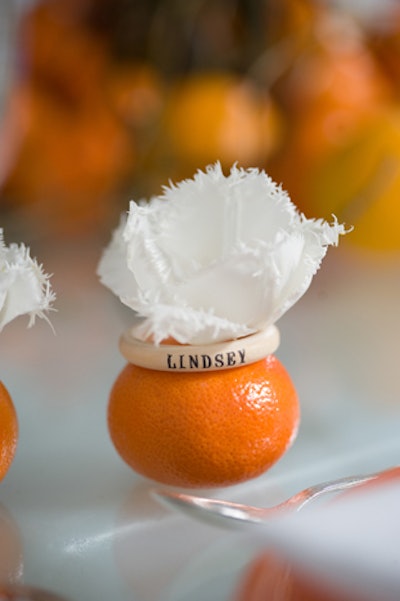 To complement a dramatic branch centerpiece dotted with oranges, wooden napkin rings printed with guests’ names were placed atop mini oranges and topped with fringed white tulip petals.