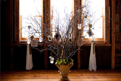 Set up inside a rustic New England barn, an escort card tree made with branches, mirrors, and moss holds hand-lettered kraft paper envelopes, secured with tiny clothespins.
