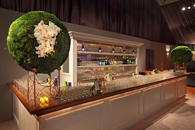 Topiary-like greenery decked with white flowers flanked a chic white bar.