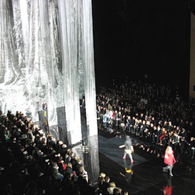 Models walked among eight translucent scrim panels—hung from the ceiling and attached to the floor—which contrasted the simple black risers and plexiglass floor.